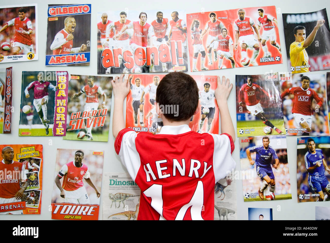 Giovani Arsenal Football sostenitore boy mettendo su poster sulla sua camera da letto a parete, London, England, Regno Unito Foto Stock
