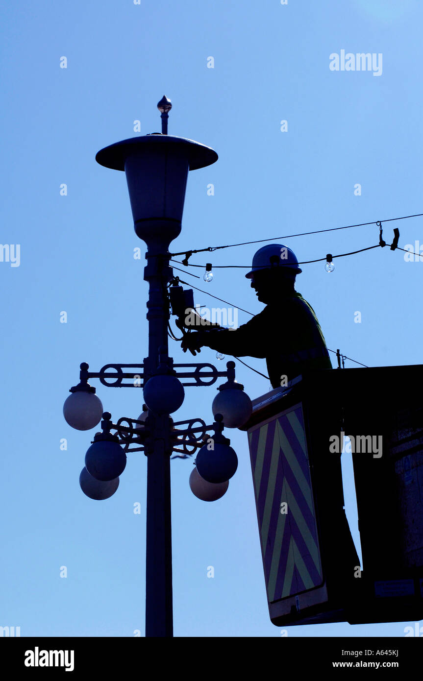 Un elettricista installazione di efficienza energetica delle lampadine sul lungomare di Eastbourne. Foto da Jim Holden. Foto Stock