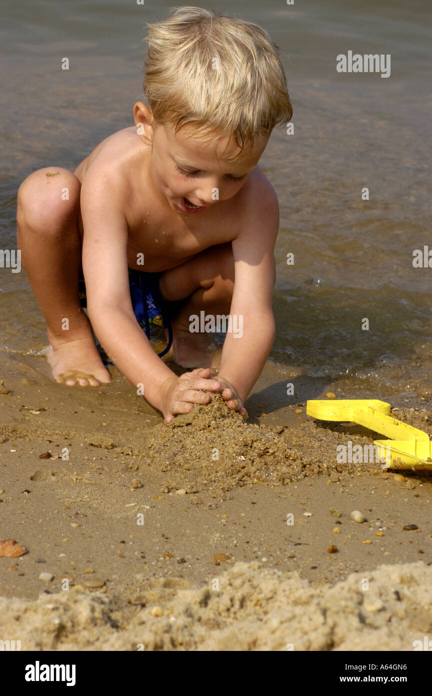 Giovane ragazzo giocando sulla spiaggia a scavare nella sabbia vacanza estiva di famiglia Foto Stock