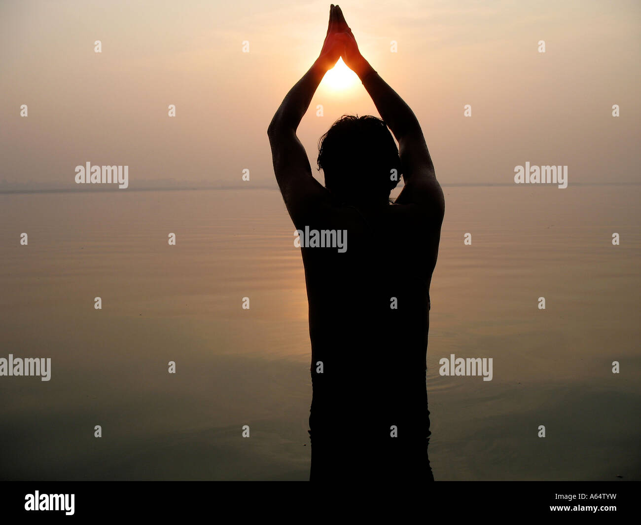 Un uomo che prega dal fiume Gange Varanasi India presso sunrise Foto Stock