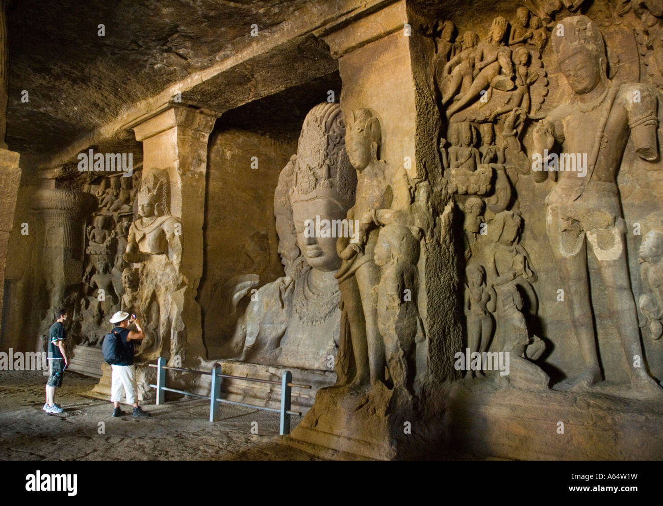 I turisti all'interno di un tempio nella grotta sull isola Elephanta un breve tragitto in barca da Mumbai in India Foto Stock
