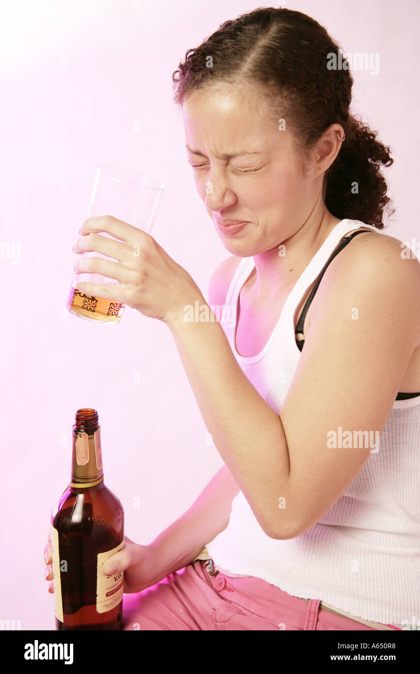 Giovane donna di bere alcolici e non esattamente di godere di essa. Foto Stock