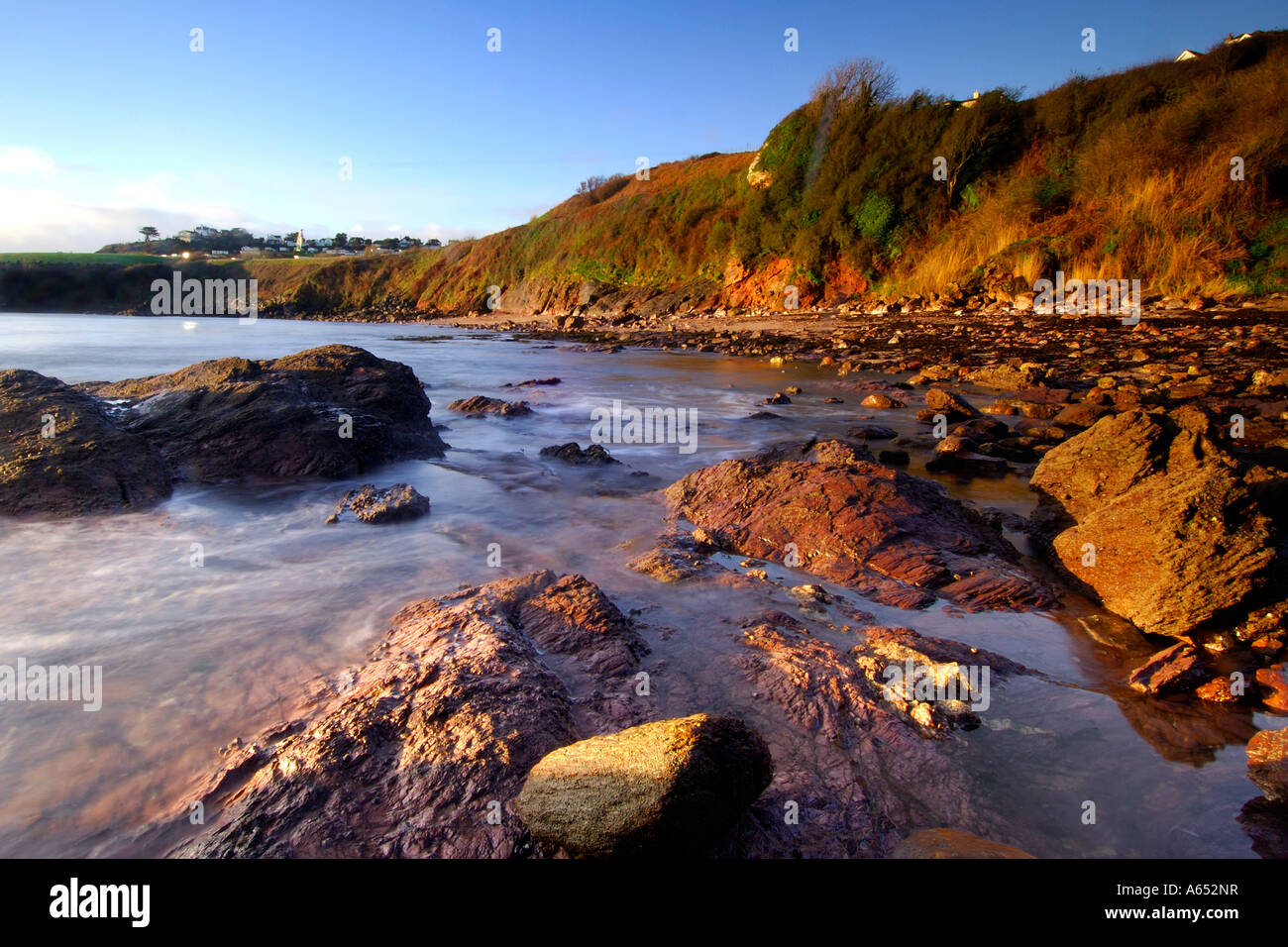 Beautiful Dawn luce a Saltern Cove vicino a Paignton Devon meridionale con il mare che turbinano intorno le rocce esposte Foto Stock