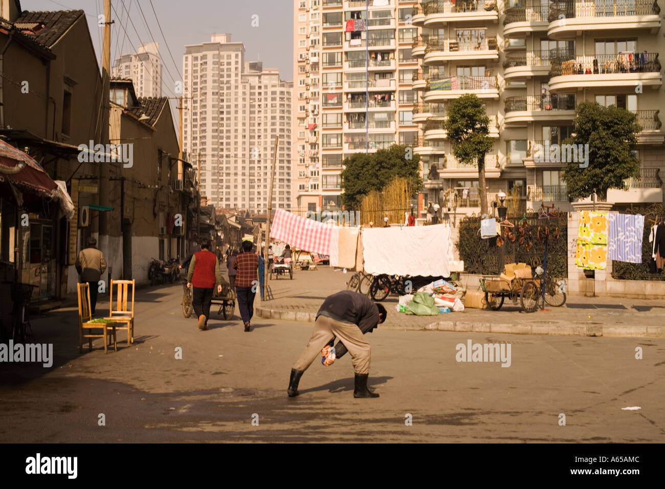 Shanghai, Cina. La città vecchia incontra il nuovo come un uomo fa il suo esercizio mattutino in strada la biancheria appesa ad asciugare Foto Stock