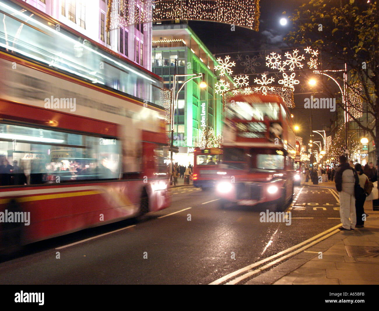 Il movimento dei buss si sfoca guidando sotto le decorazioni illuminate dall'alto a Oxford Street West End Londra poco prima del giorno di Natale Inghilterra Regno Unito Foto Stock