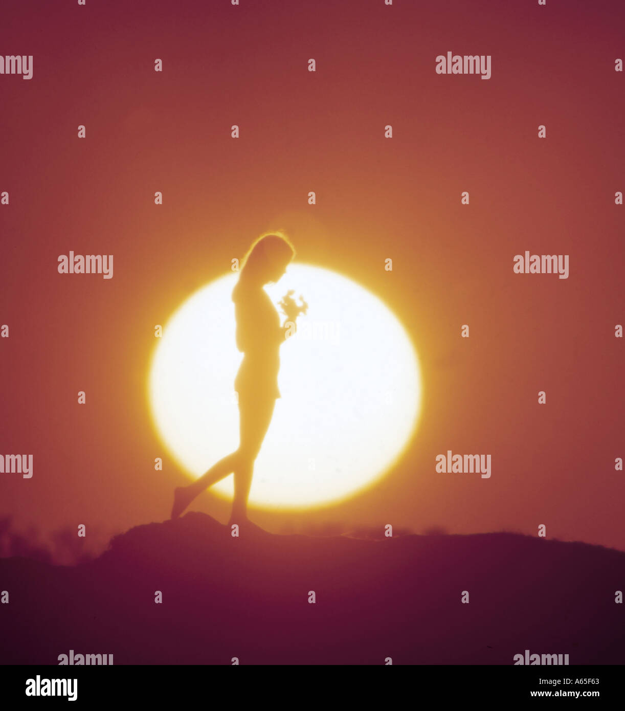 Ragazza sulla collina stagliano da enormi tramonto Foto Stock