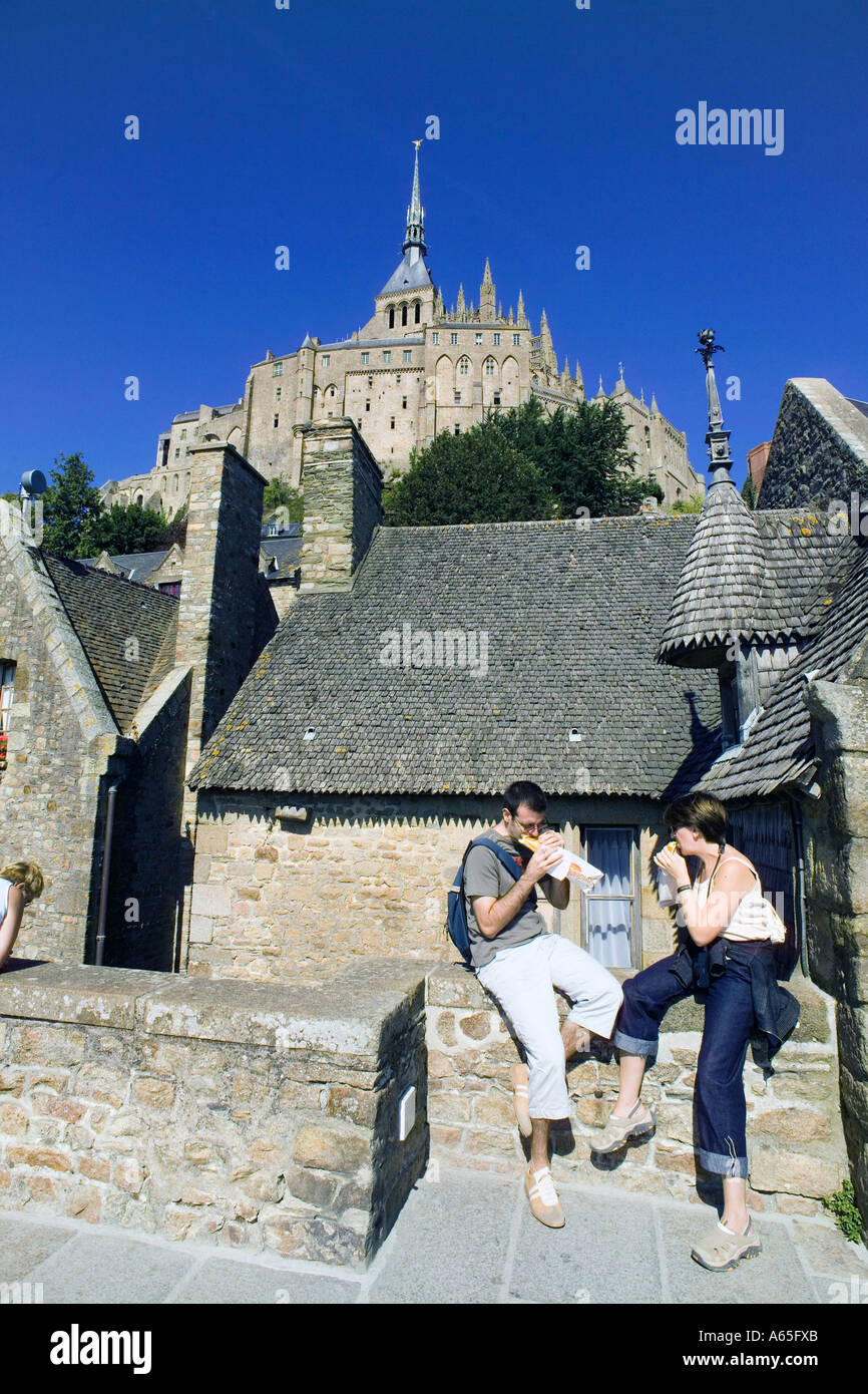 Coppia giovane mangiando panini nella parte anteriore del case antiche Mont St Michel Normandia Francia Europa Foto Stock