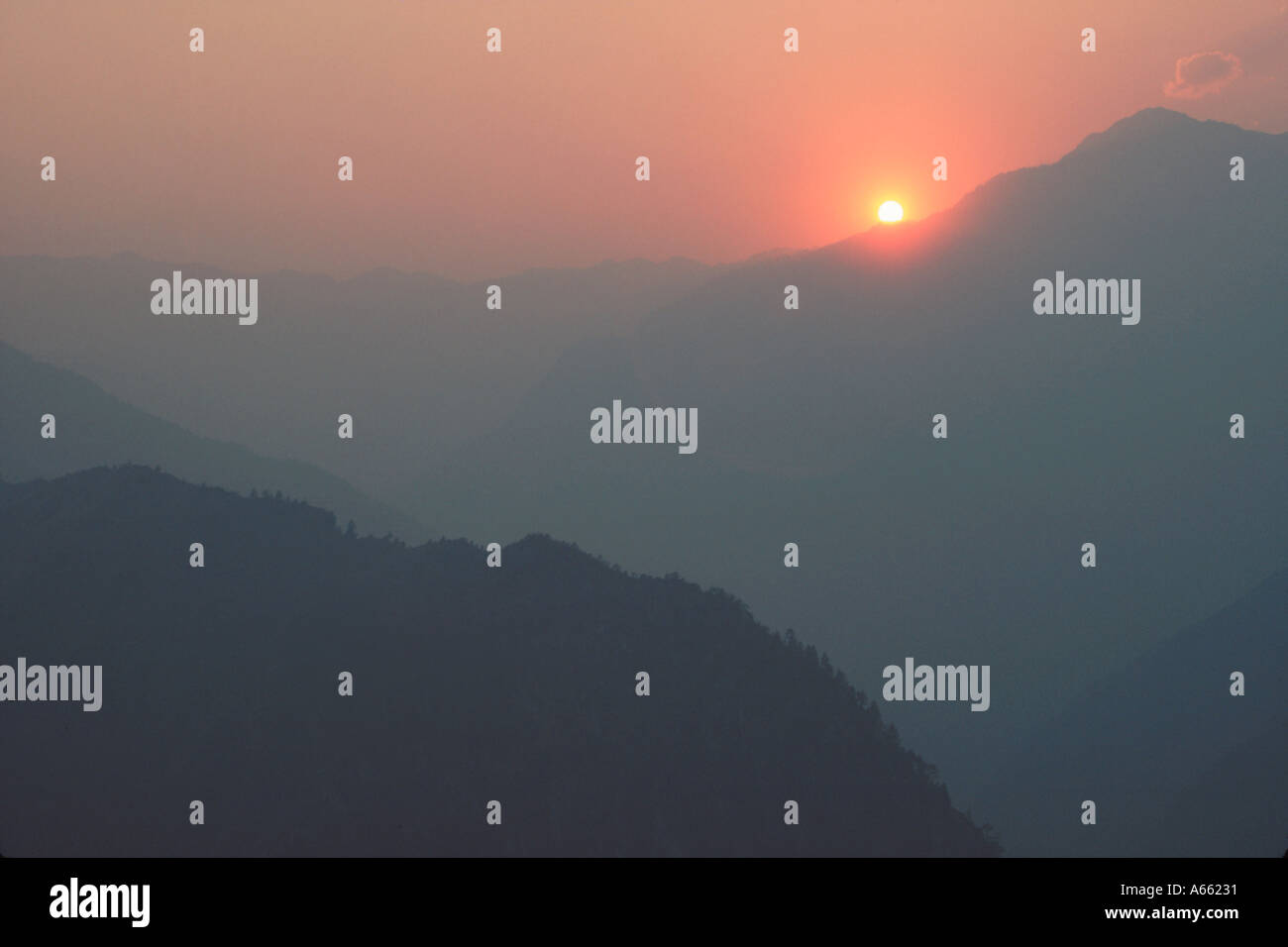 Il sole affonda dietro le colline che fiancheggiano la valle di Langtang Nepal settentrionale Foto Stock