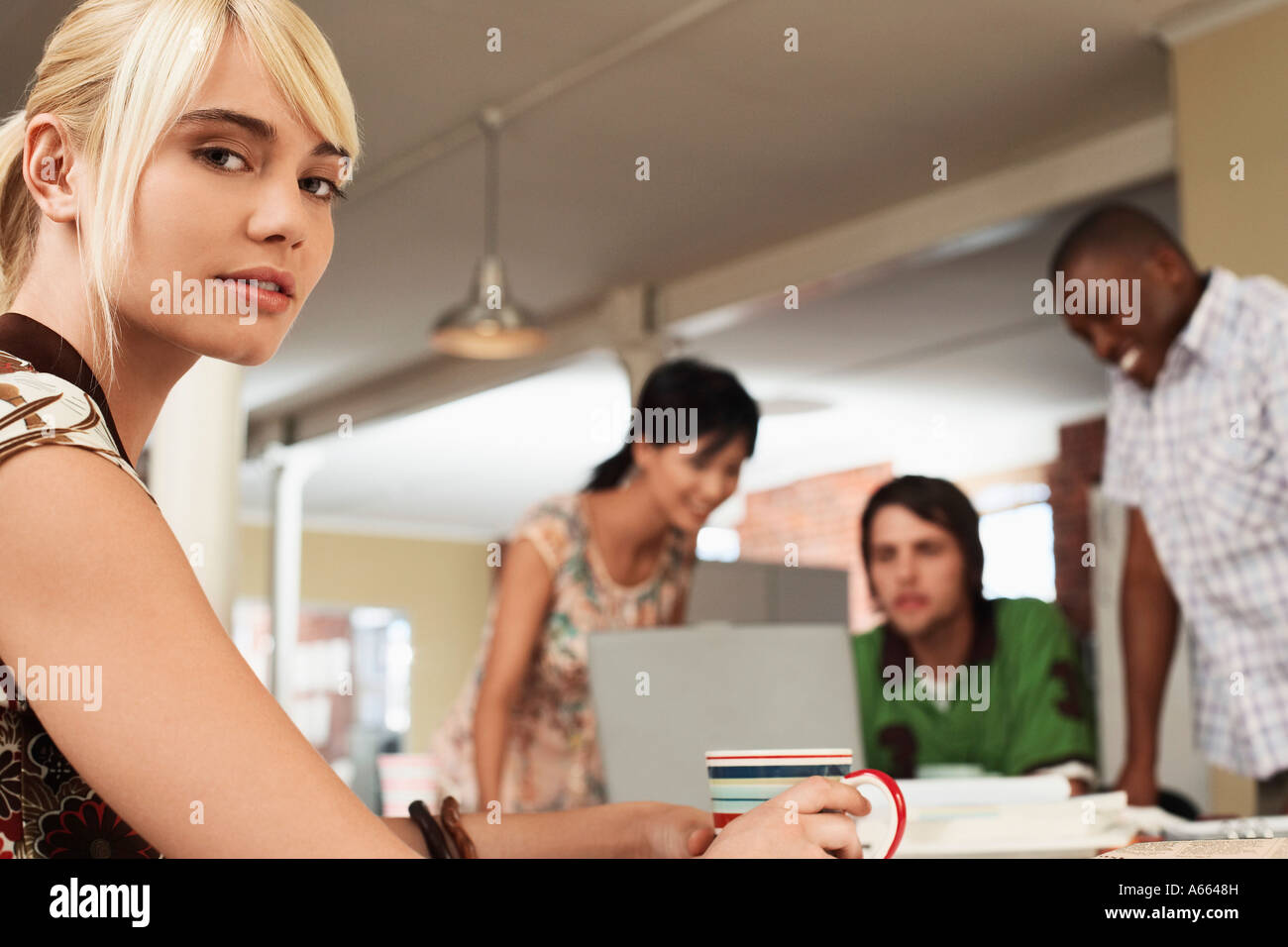 Donna coppa di ritegno, con tre persone attorno al computer in background. Foto Stock