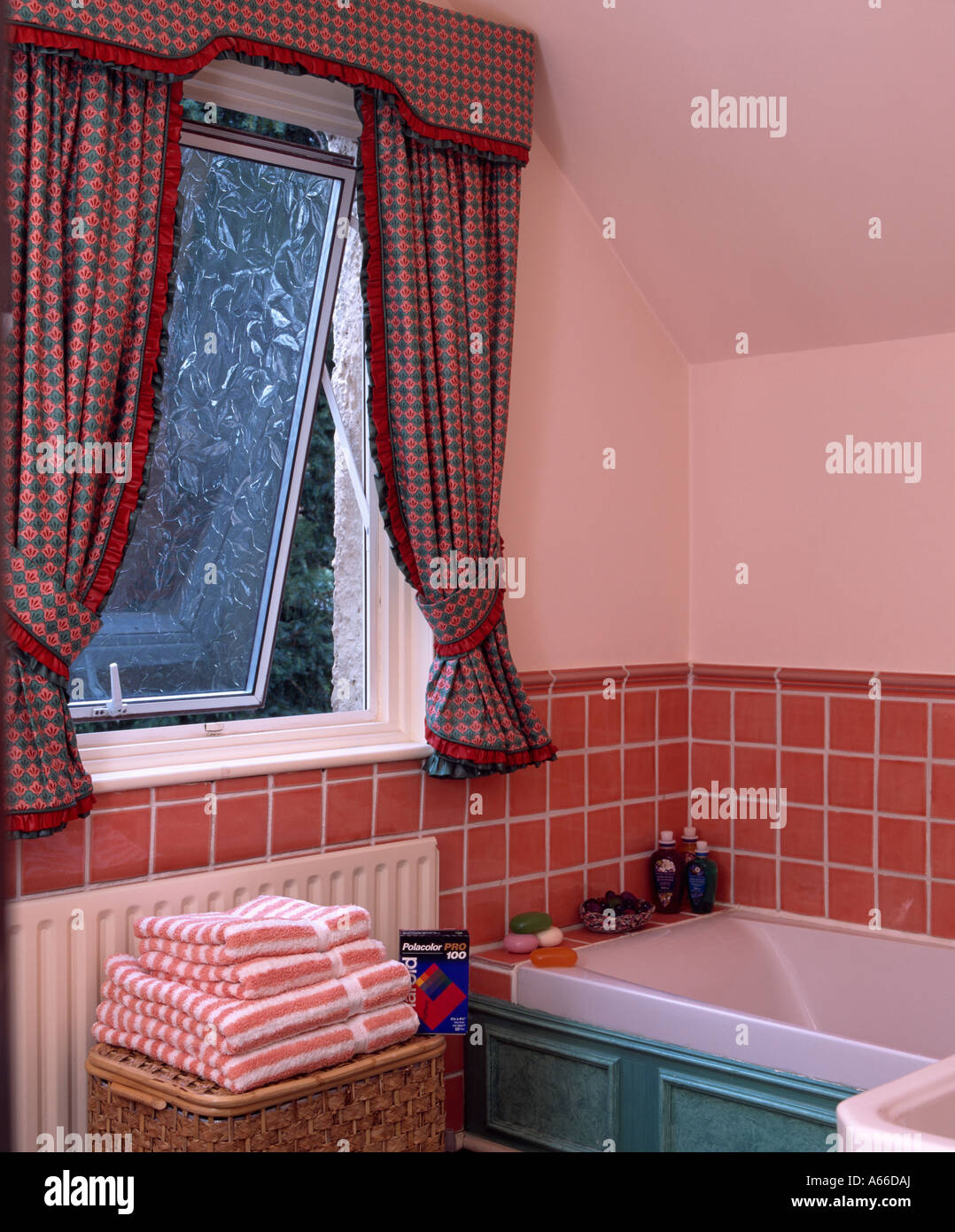Aprire la finestra sopra il bagno con tegole rosse e surround e la pila di asciugamani rosa Foto Stock