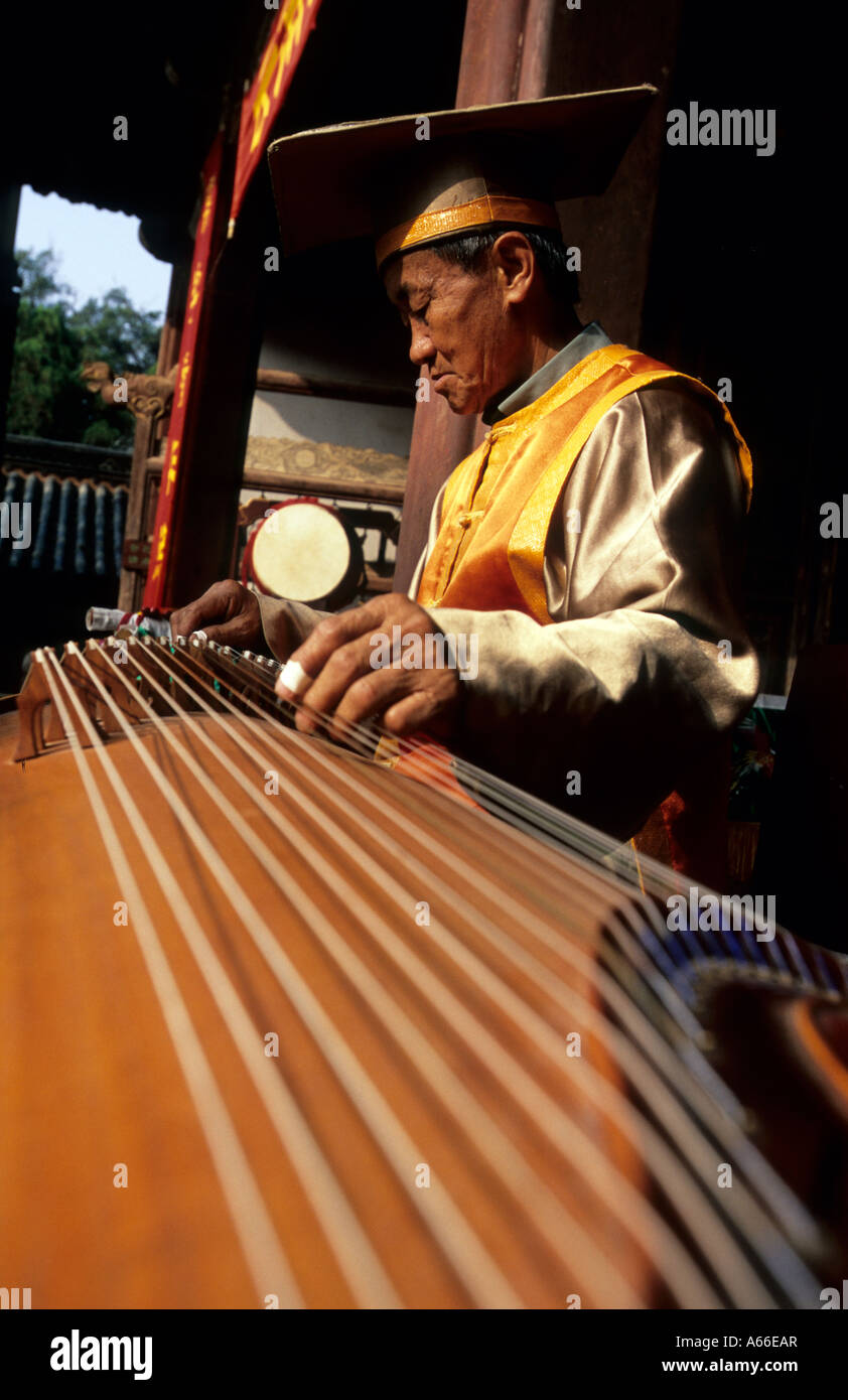 Musicista in abito tradizionale la riproduzione del Guzheng (Cinese cetra) nel tempio confuciano. Jianshui, Cina. Foto Stock