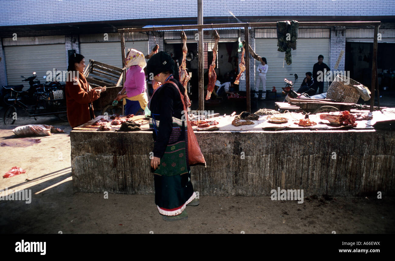 Yao donna cammina lungo la sezione di carne del mercato di Menghai. Xishuangbanna, Yunnan in Cina. Foto Stock