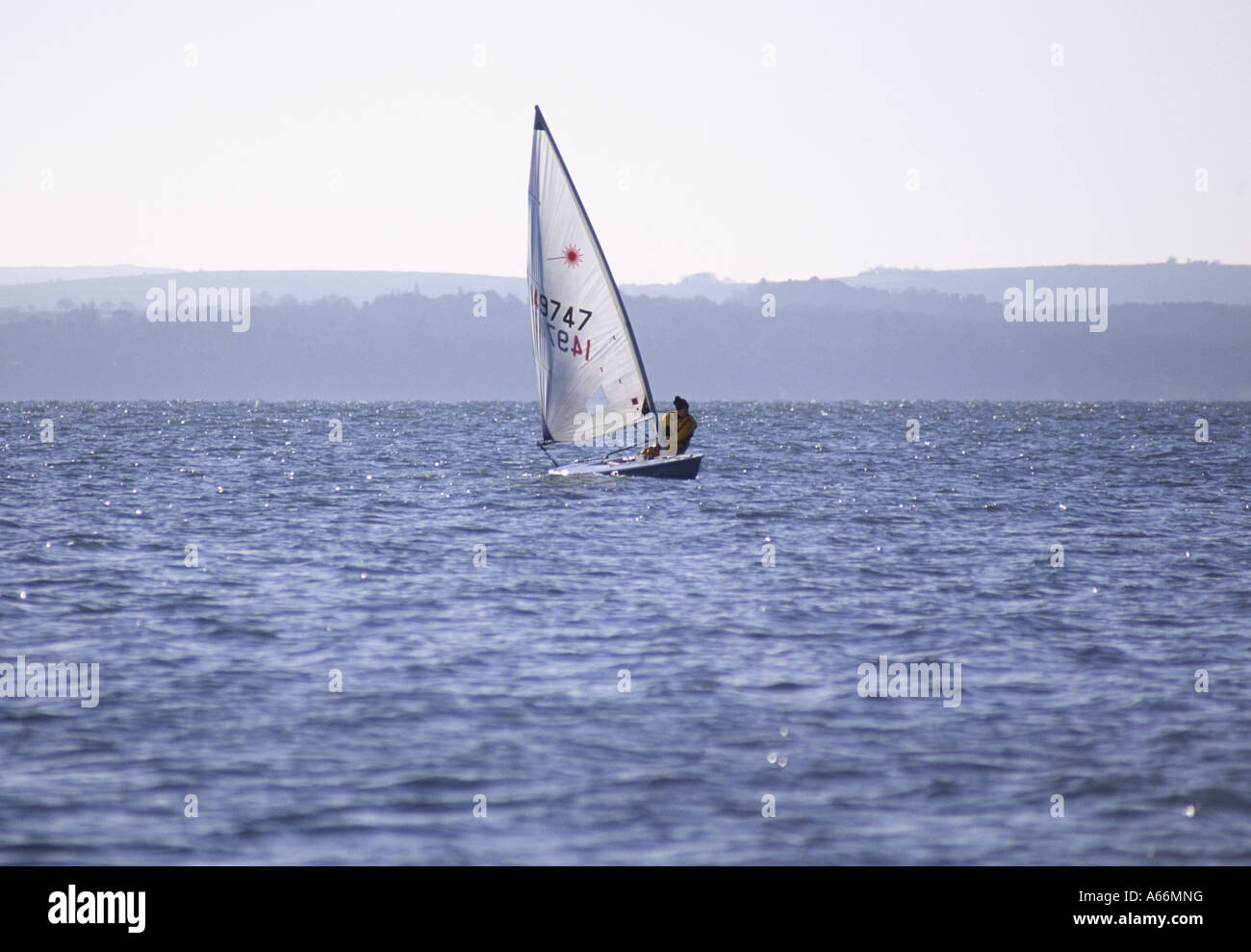 Lone uomo vela un po' un uomo in barca a vela sul Solent acqua, immerso nei primi giorni di sole primaverile, dalla baia di Stokes, Gosport, Engl Foto Stock