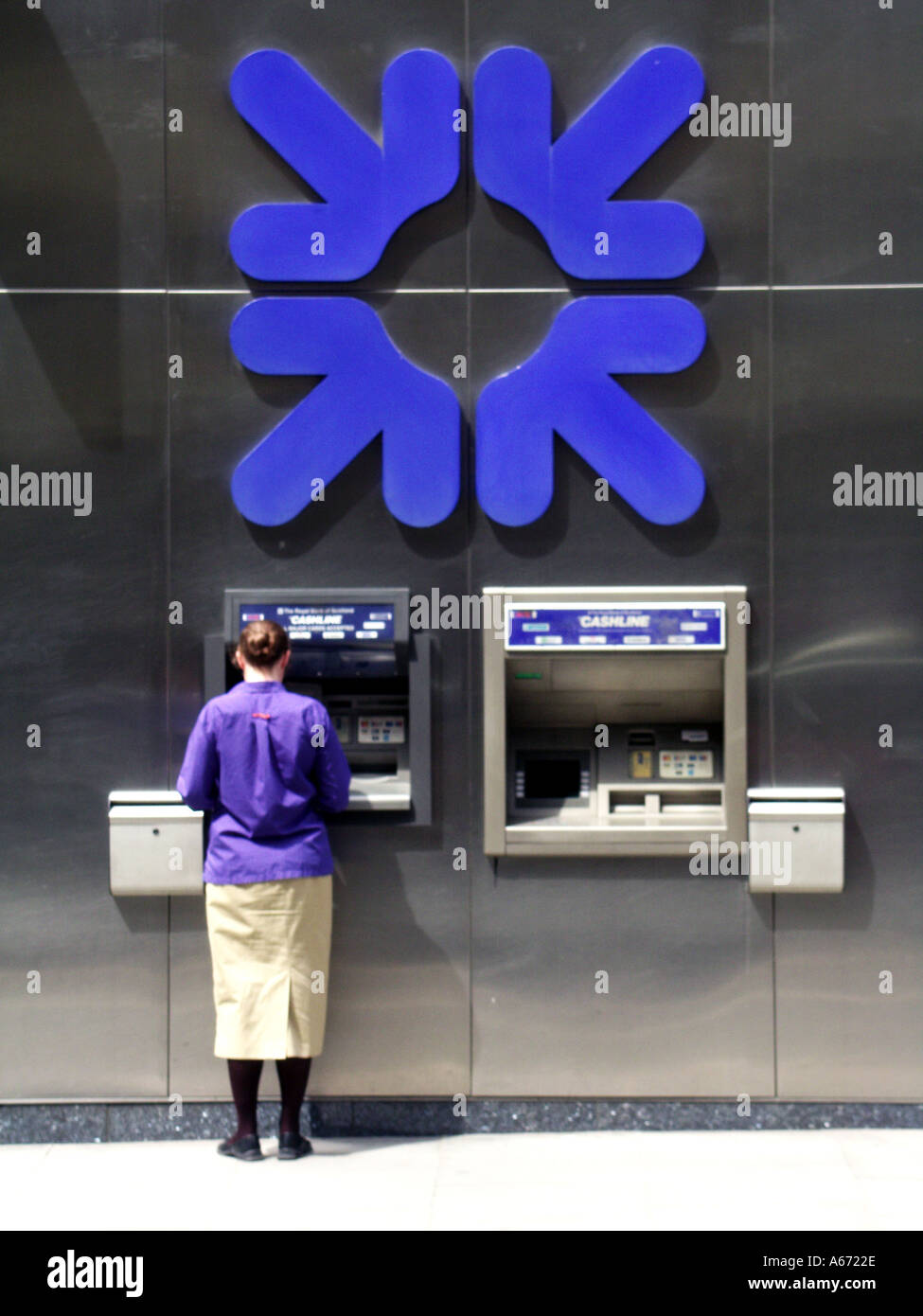 Royal Bank of Scotland grande logo aziendale blu sulla parete vista posteriore donna che utilizza un foro bancomat nella pavimentazione del distributore di contanti a City of London Inghilterra Regno Unito Foto Stock