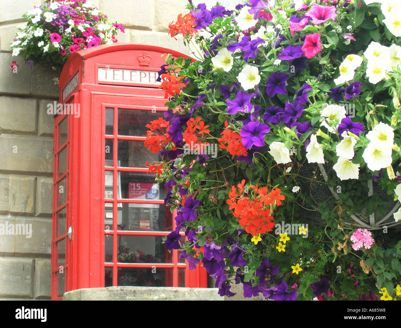 Dettaglio di un singolo telefono rosso box coperti con cesti floreali pendenti Glastonbury Somerset Inghilterra Foto Stock