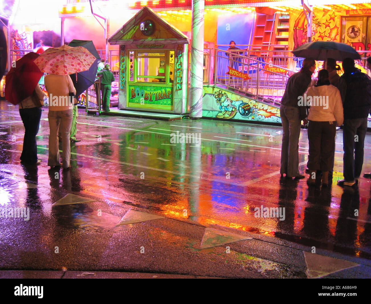 Fairground Ride con box office riflessa nel pavimento bagnato Foto Stock