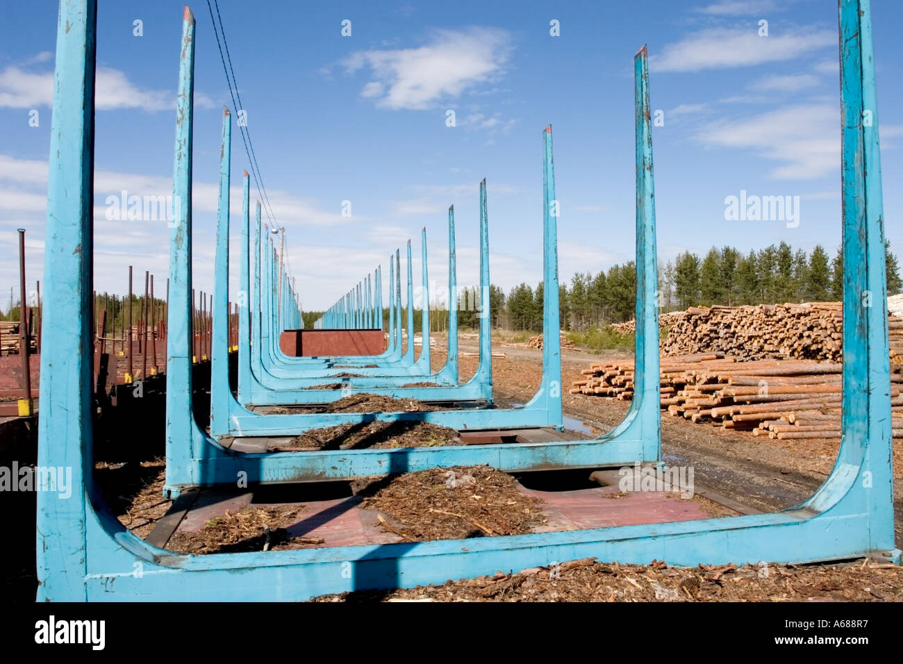 Empty railroad pianali atti con picchetti per il trasporto di registri e di legname e di pile di tronchi pronti per essere caricati al treno , Finlandia Foto Stock