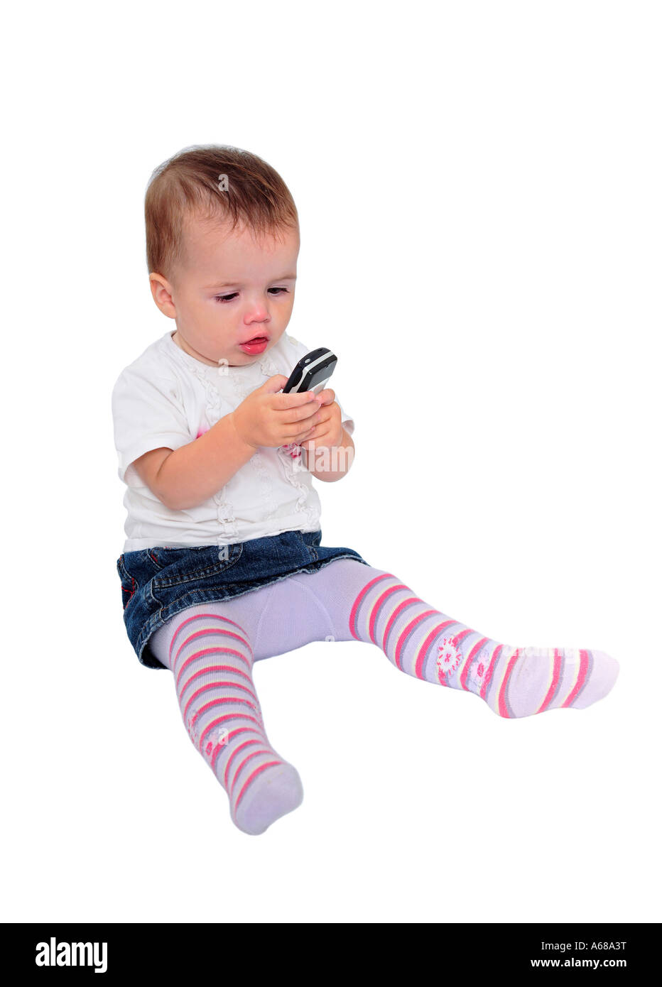 Foto di isolato di giovani simpatici baby girl con capelli castani seduti l'invio di messaggi di testo sul suo telefono mobile o cellulare Foto Stock