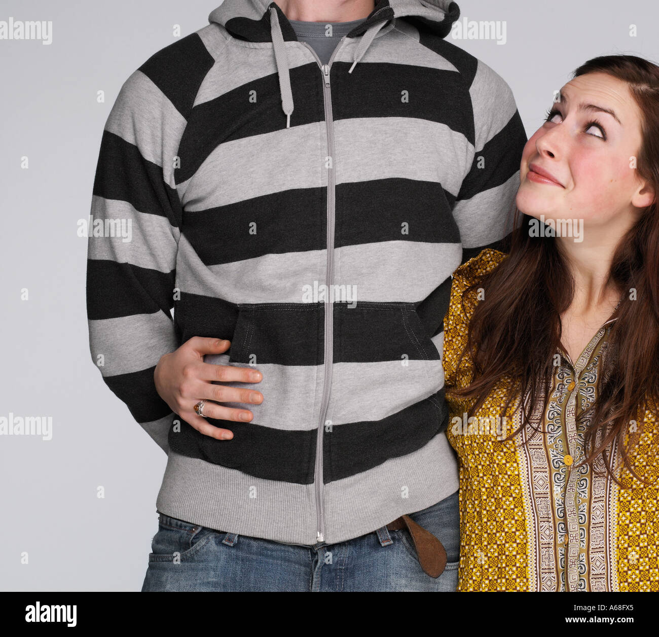 Corto donna con il suo braccio intorno a un alto uomo cercando adoringly Foto Stock