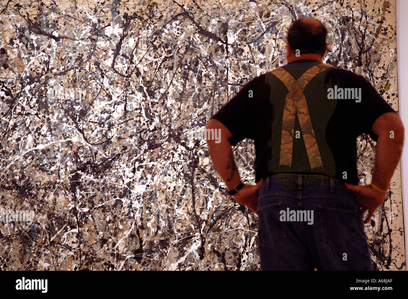 Uomo con abbinamento di bretelle in piedi di fronte a Jackson Pollock presso il recentemente riaperto il Museo di Arte Moderna di New Yor Foto Stock