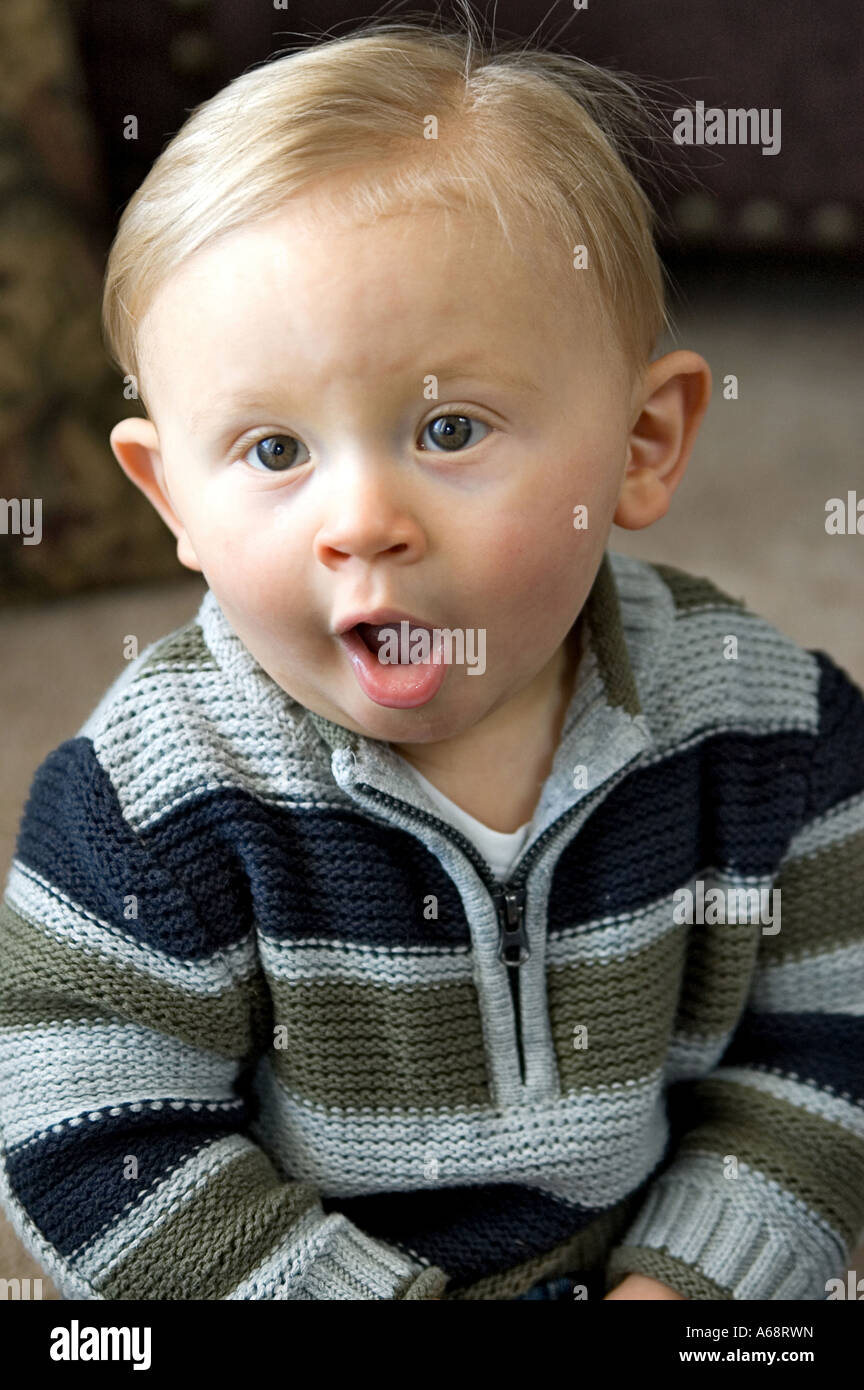 Un anno di età baby boy in un maglione con la bocca aperta a sorpresa Foto Stock
