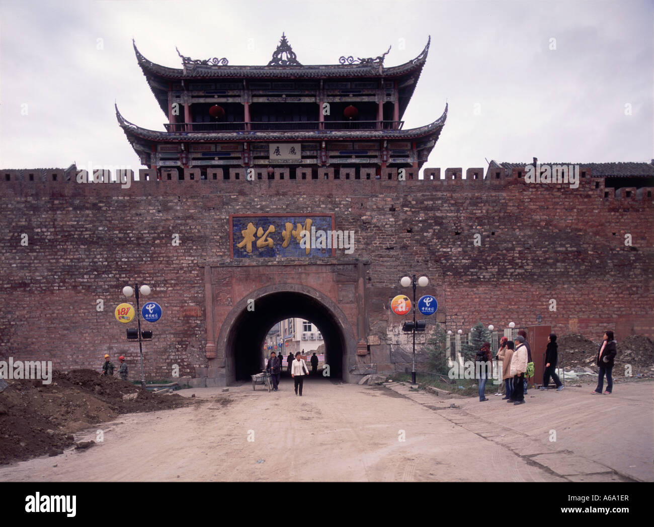 Cina, Sichuan, Songpan, le persone camminare sotto arco di Ming-dynasty porta est ornata, gronda rovesciata sul padiglione Foto Stock