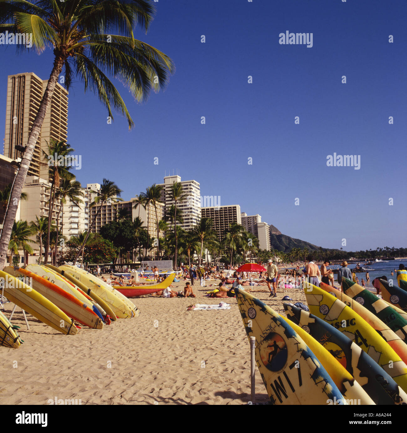 Vista lungo la spiaggia di Waikiki con tavole da surf impilati in rastrelliere lungo sulle sabbie Honolulu Oahu Island Hawaii Foto Stock