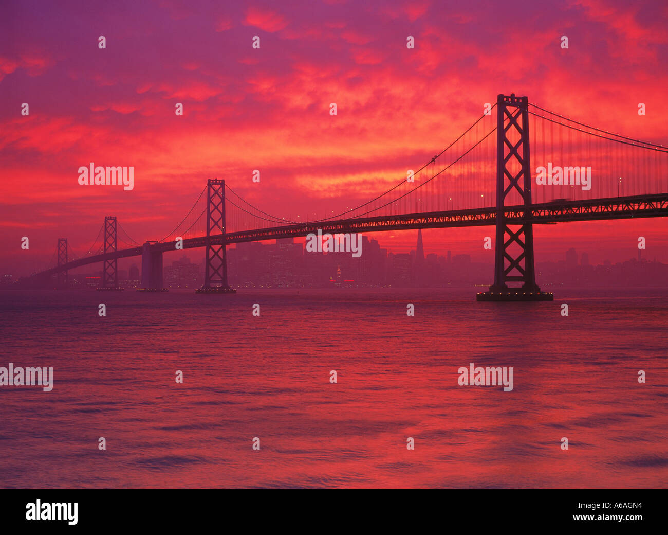 Oakland Bay Bridge e la baia di San Francisco in rosso luminoso Cielo di tramonto Foto Stock