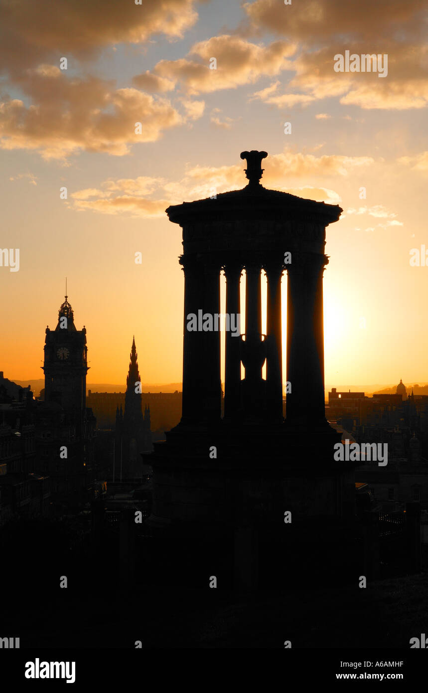 Tramonto su una silhouette della città di Edimburgo con Dugald Stewart monumento e il Balmoral Hotel da Calton Hill Foto Stock