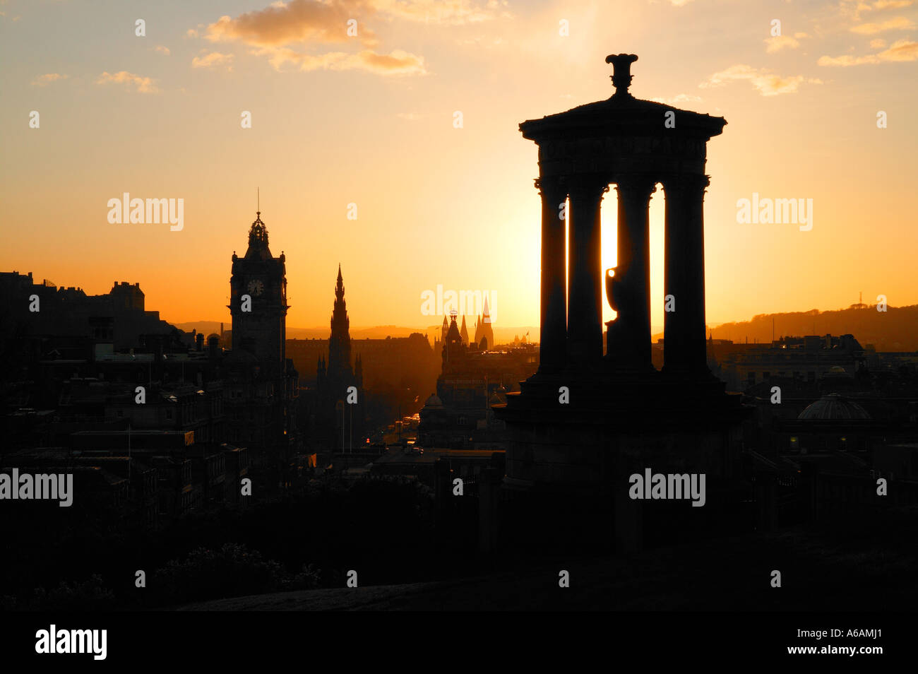 Tramonto su una silhouette della città di Edimburgo con Dugald Stewart monumento e il Balmoral Hotel da Calton Hill Foto Stock