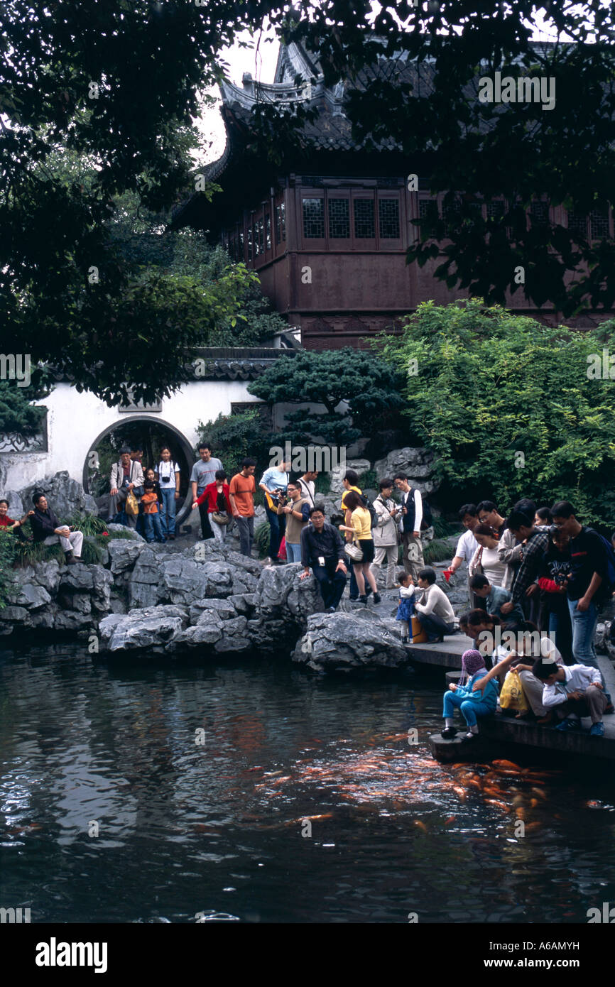 Giardini di Yu (Yu Yuan), i visitatori sulla piattaforma di pietra sopra il lago classic tai hu formazioni rocciose e alimentare pesce Foto Stock