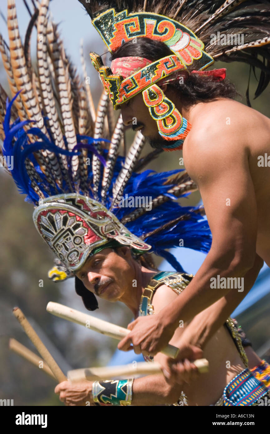 Due uomini vestiti in tradizionale copricapo azteco, i tamburi per uno spettacolo di danza. Foto Stock