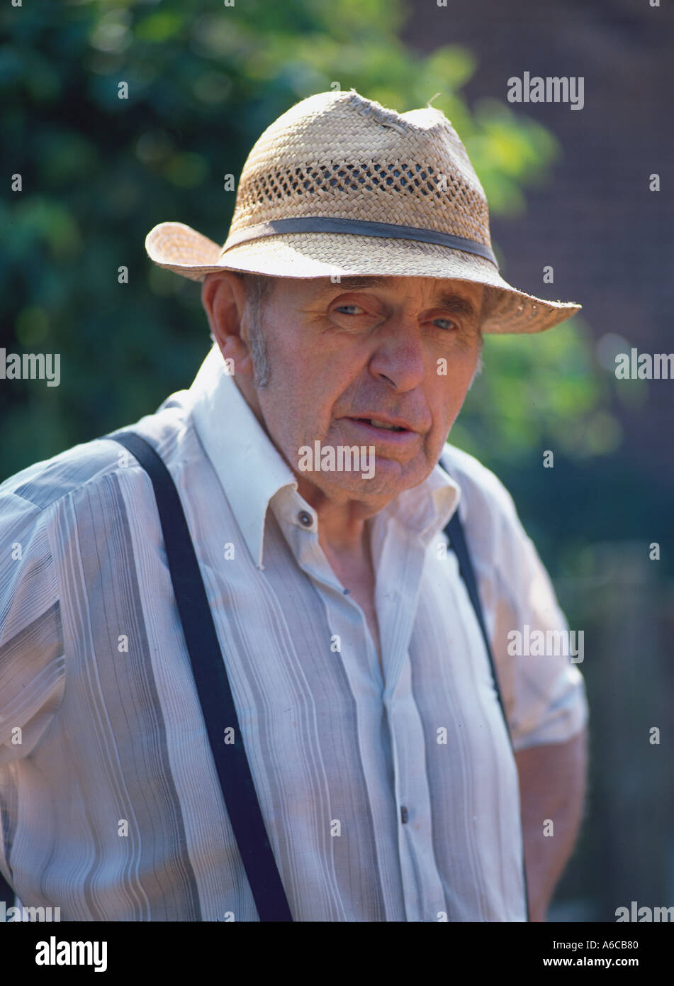 Elderley uomo che indossa cappello di paglia e bretelle Foto stock - Alamy