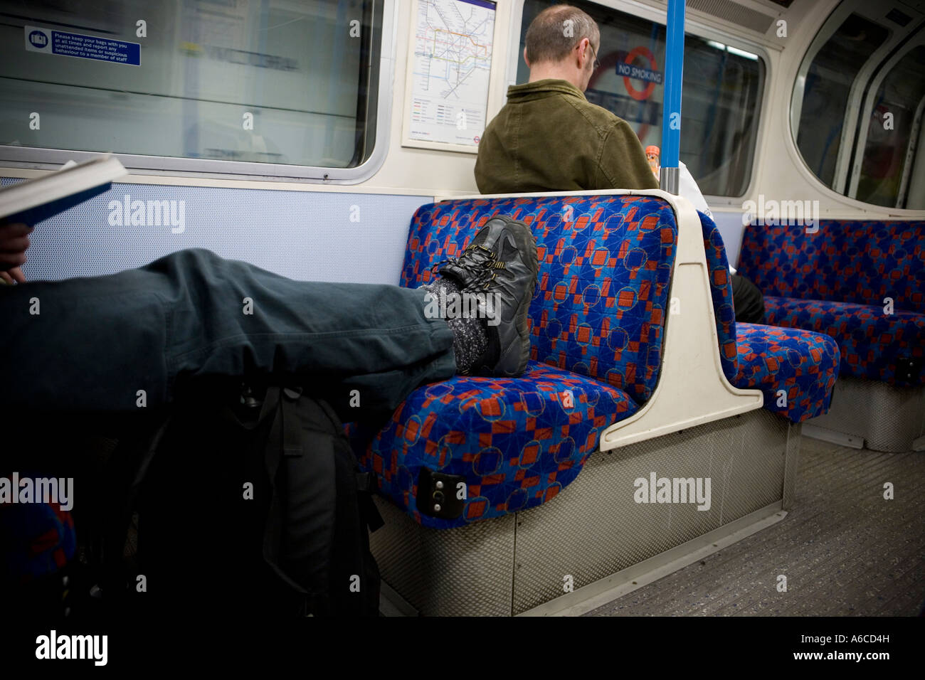 L'uomo con i piedi sul sedile sul treno del tubo Foto Stock