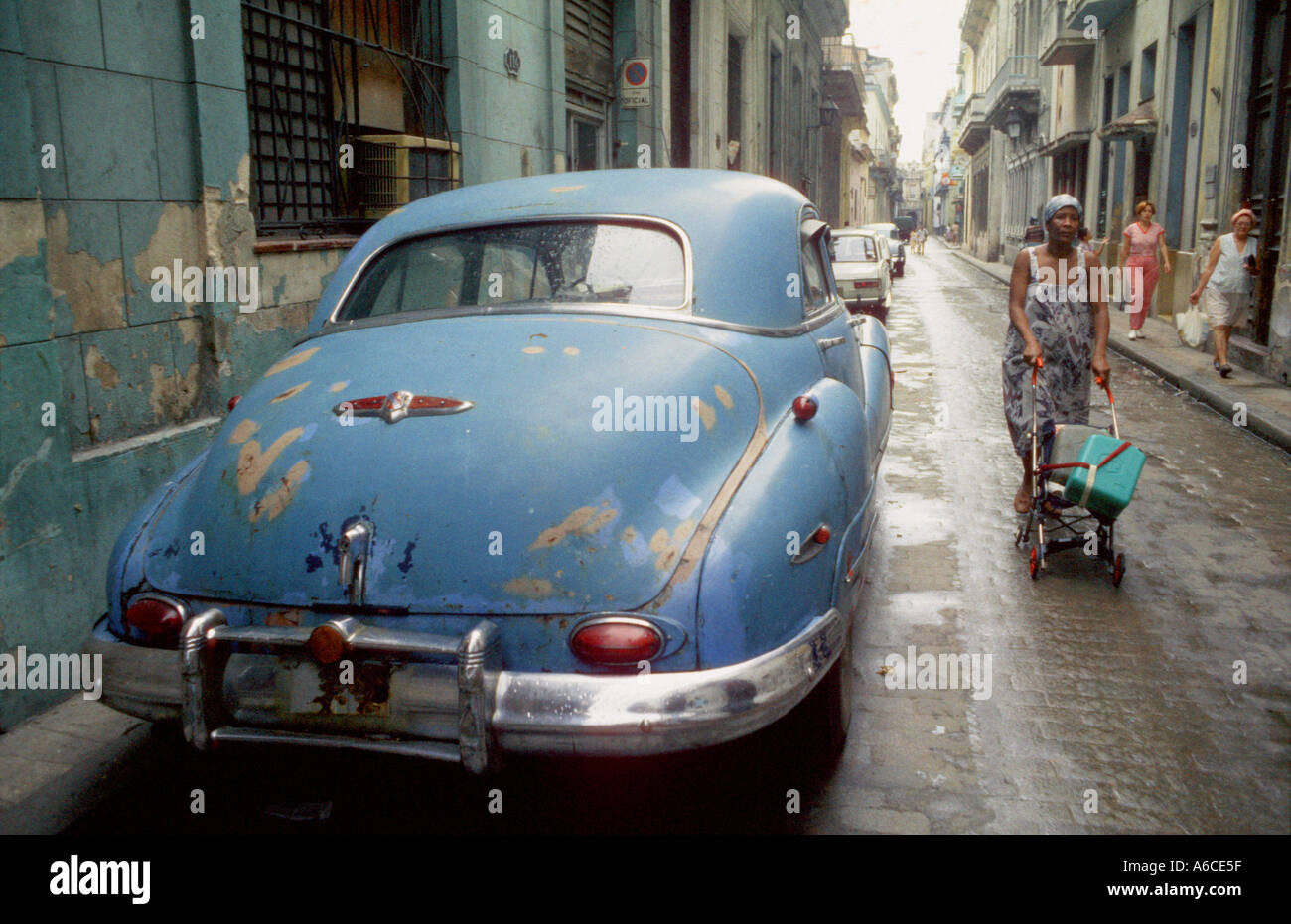 Una donna usa un bambino passeggino per il trasporto di acqua in Havana Cuba la vettura è lei che passa è una degli anni cinquanta era Buick Foto Stock