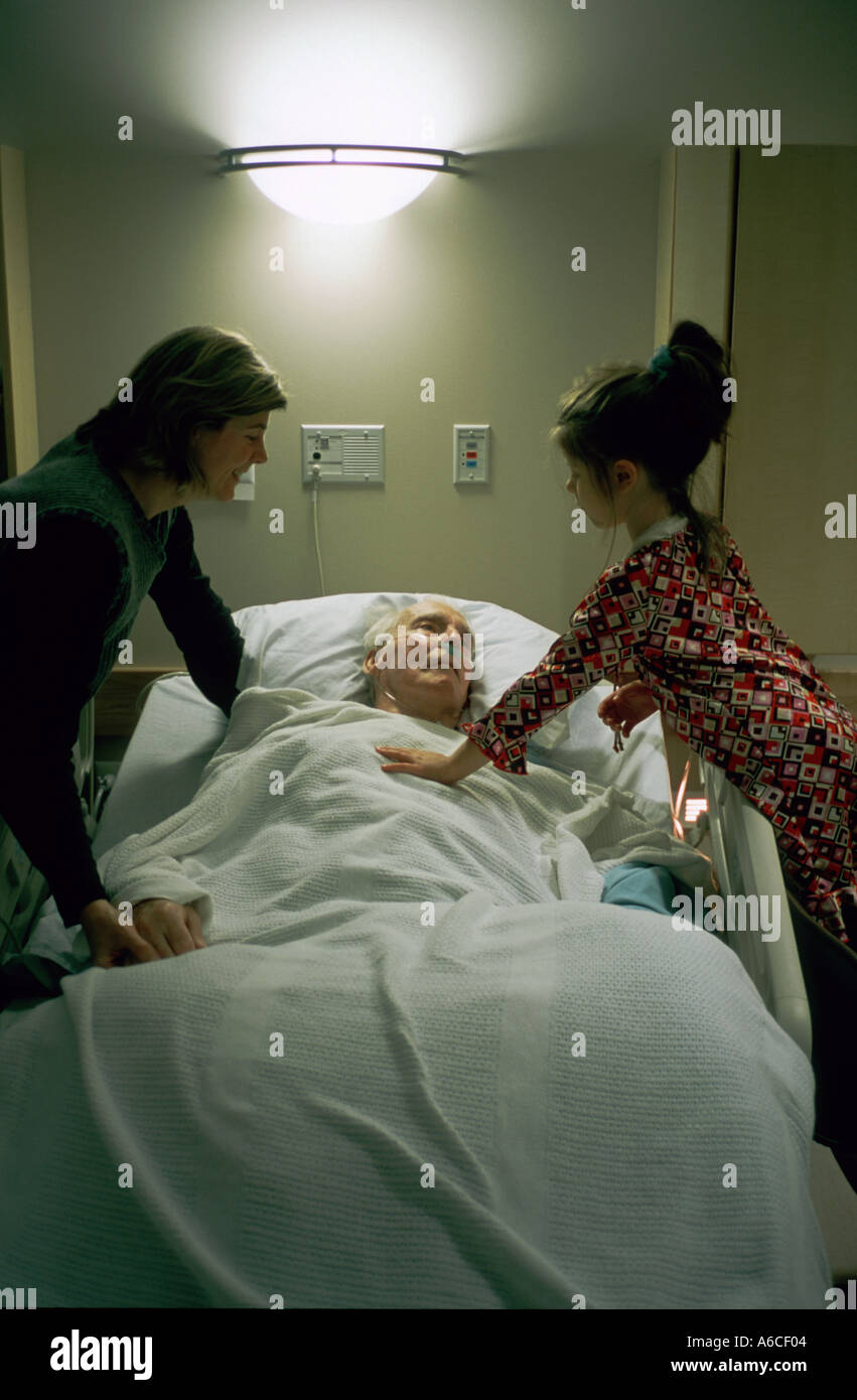 La figlia e la figlia di grand consolante il nonno che stabilisce nel letto di ospedale Foto Stock