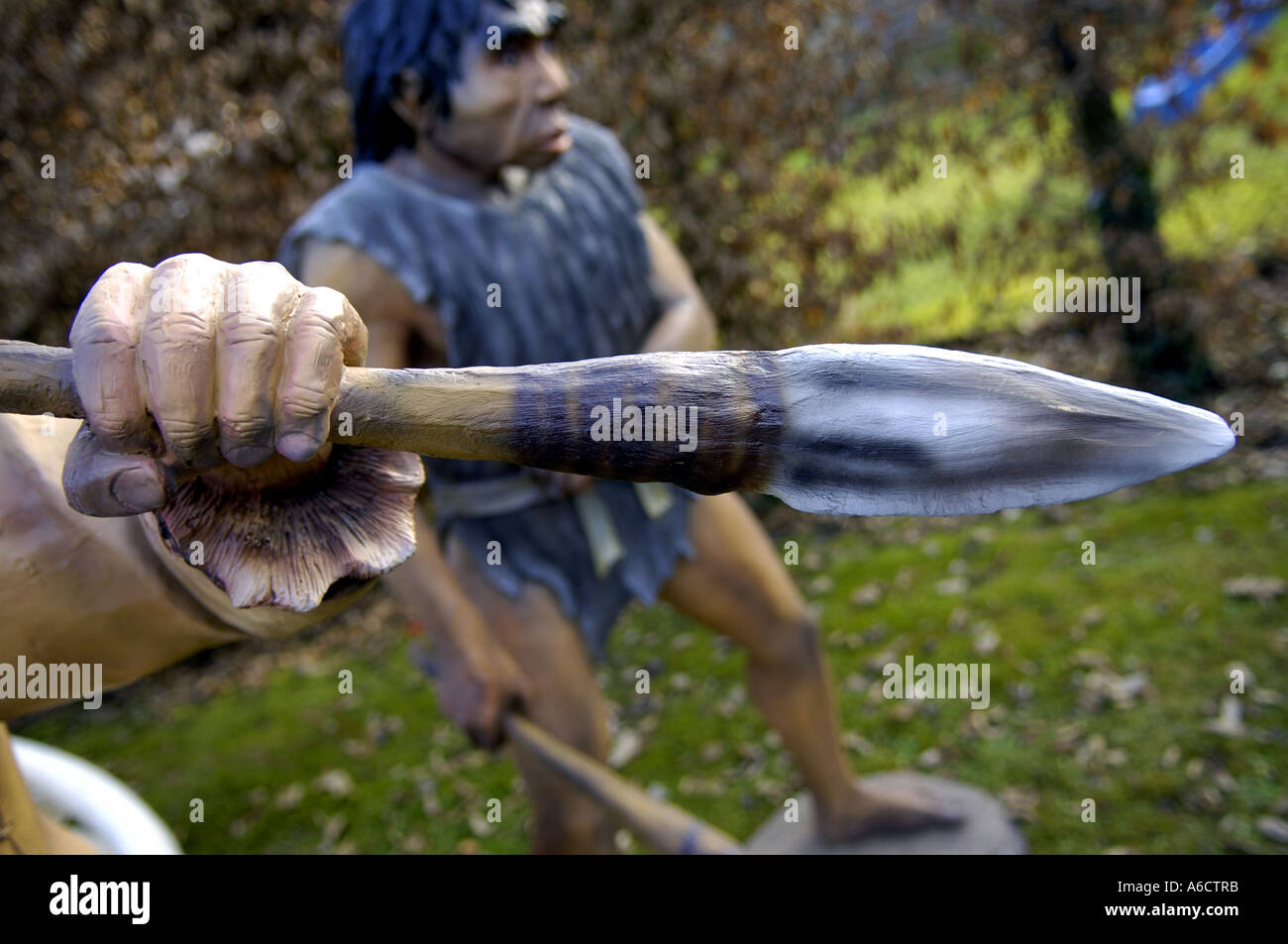 Preistorici faccia di testa grande occhio marrone uomo umano maschio umanoide armati di Neanderthal hunter lancia arma kill attacco Foto Stock