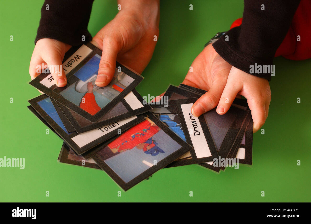 Schede di insegnamento essendo tenuto da un bambino e i genitori le mani sul piano del tavolo Foto Stock