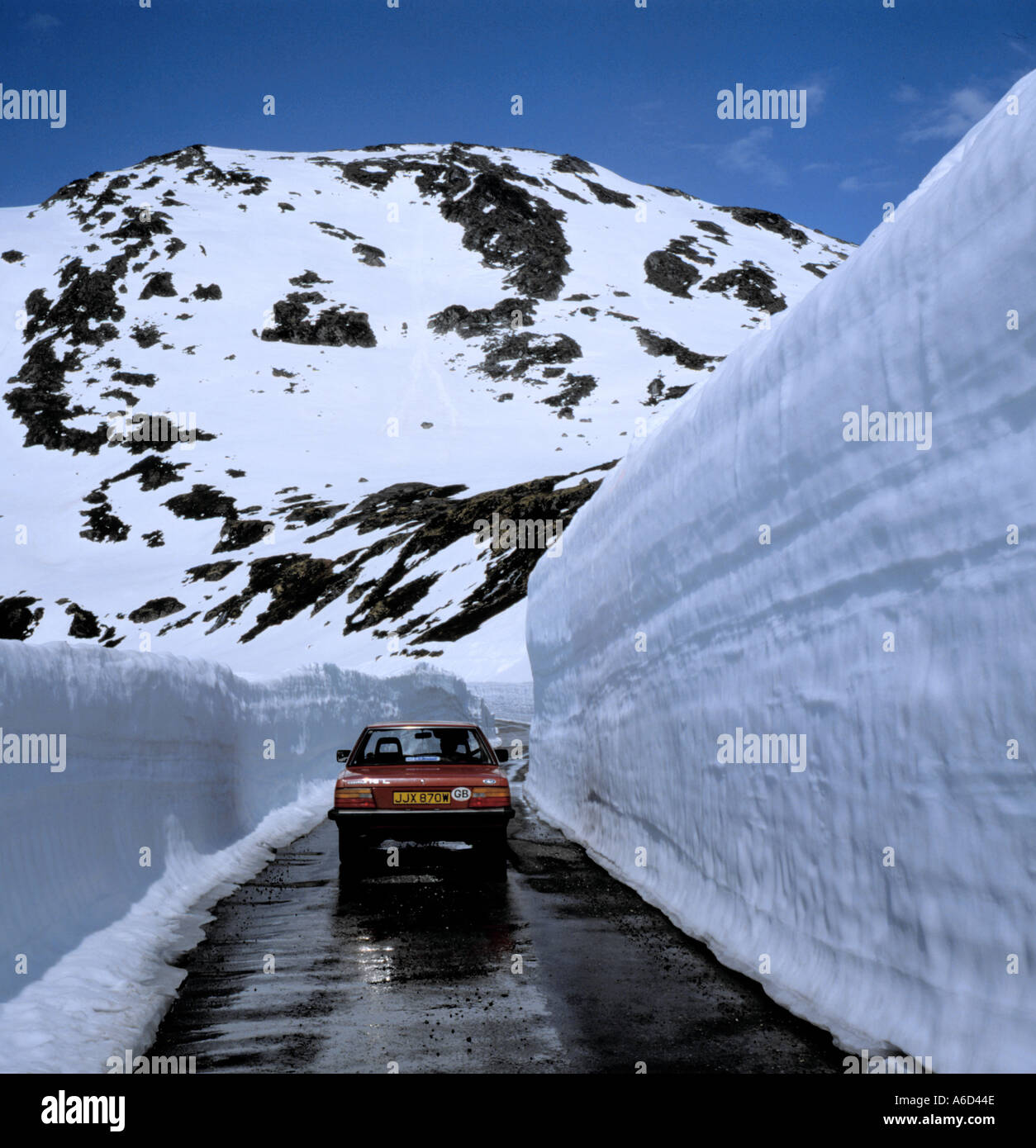 Auto sulla strada con neve a ciascun lato ai primi di giugno, Dalsnibba al di sotto e al di sopra di Geiranger, Møre og Romsdal, Norvegia. Foto Stock