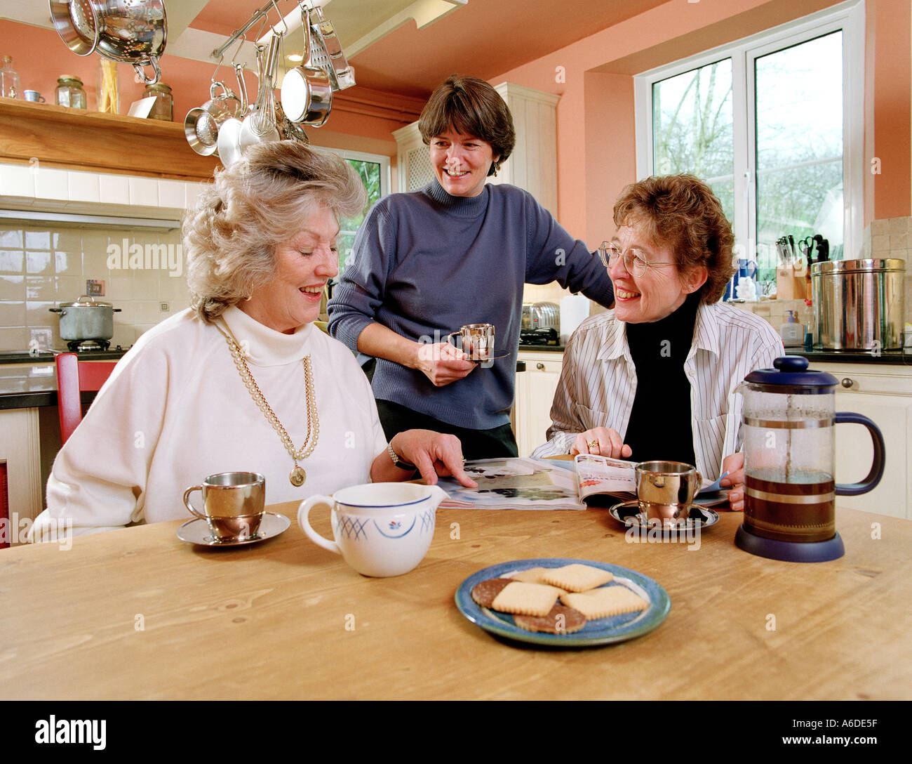 Tre donne di mezza età in cucina con accessori per caffè e magazzino Foto Stock