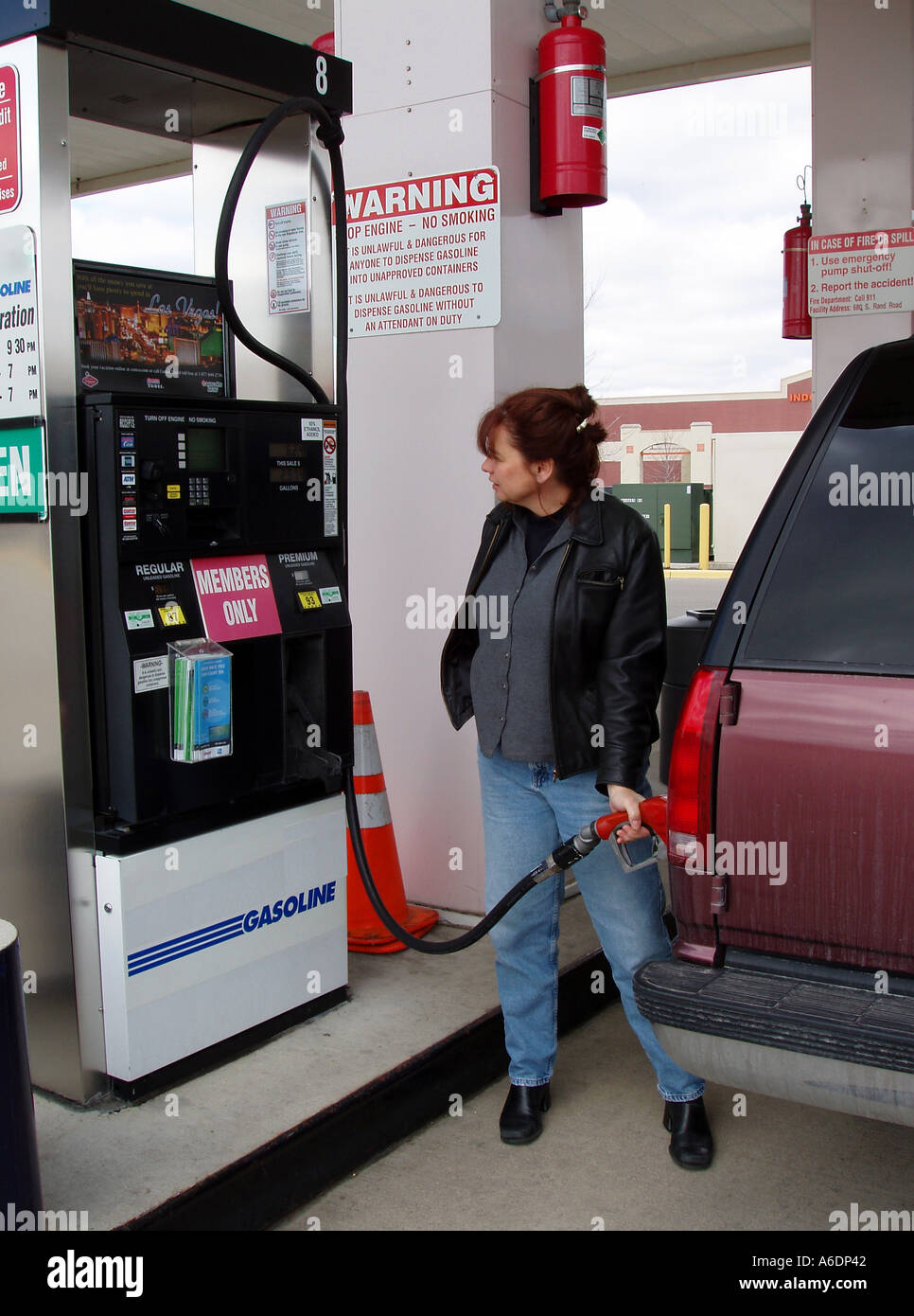 Donna gas di riempimento guzzling Chevy Suburban alla stazione di benzina Foto Stock