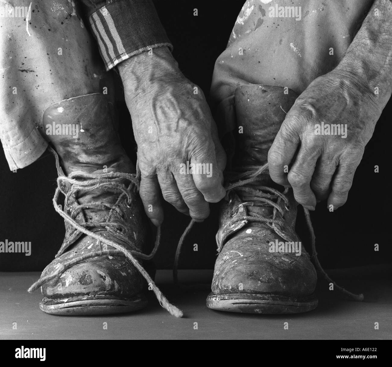 Un vecchio mans mani la legatura i suoi stivali da lavoro Foto Stock