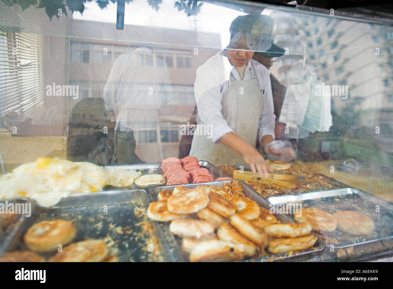 Cina Pechino Chef in vetrina ristorante prepara panini colazione di pane uova fritte e Spam Foto Stock