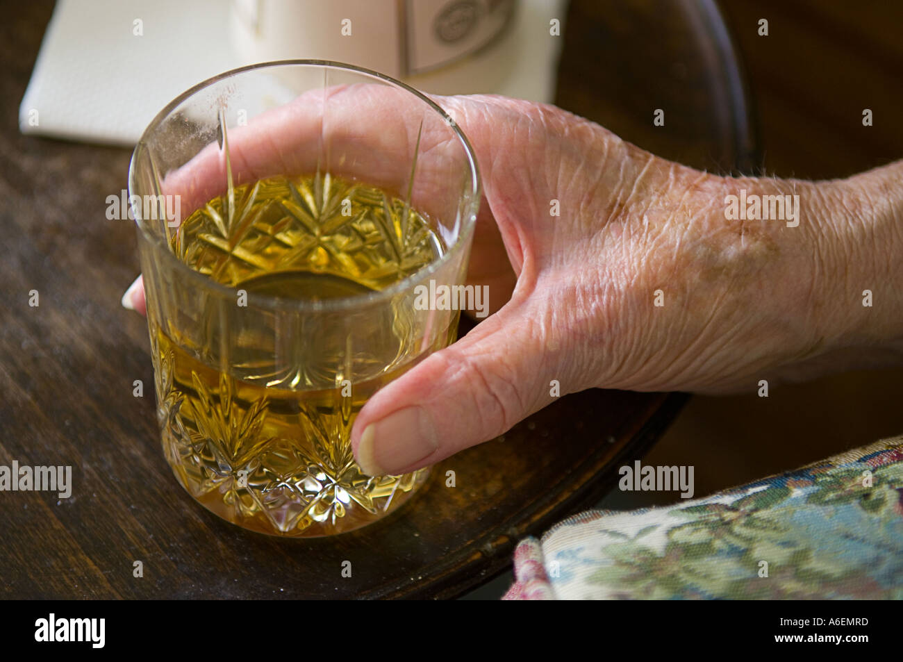 Close up della vecchia signora mano che trattiene il vetro del whisky Foto Stock