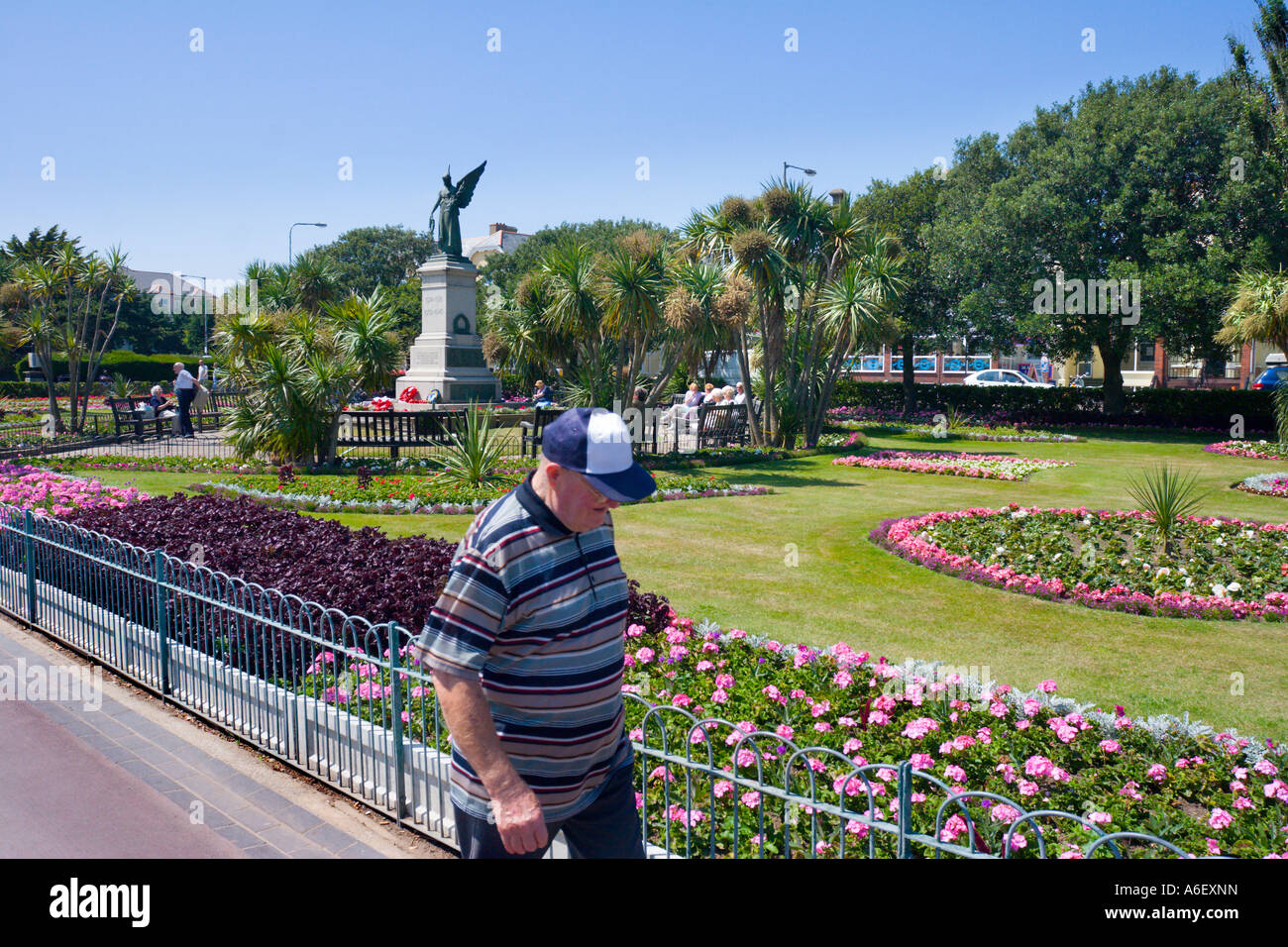 Un OAP passeggiate passato ben tenuti giardini sul CLACTON FRONTE MARE IN ESTATE Foto Stock