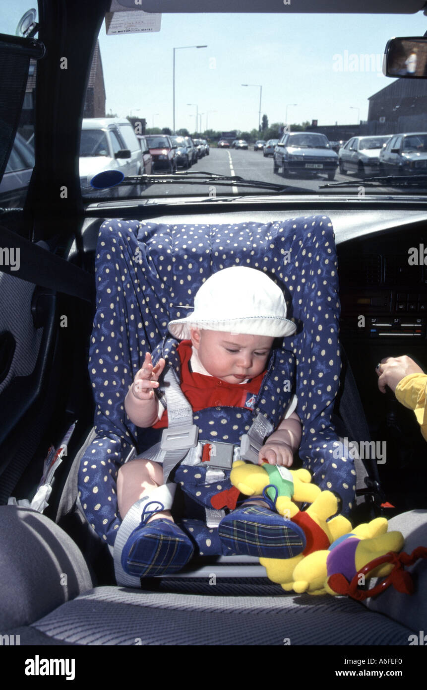 Seggiolino di sicurezza per auto per bambini rivolto all'indietro, come montato nell'archivio storico 1996, del neonato che viaggia in auto della madre lungo la strada trafficata Inghilterra Regno Unito Foto Stock