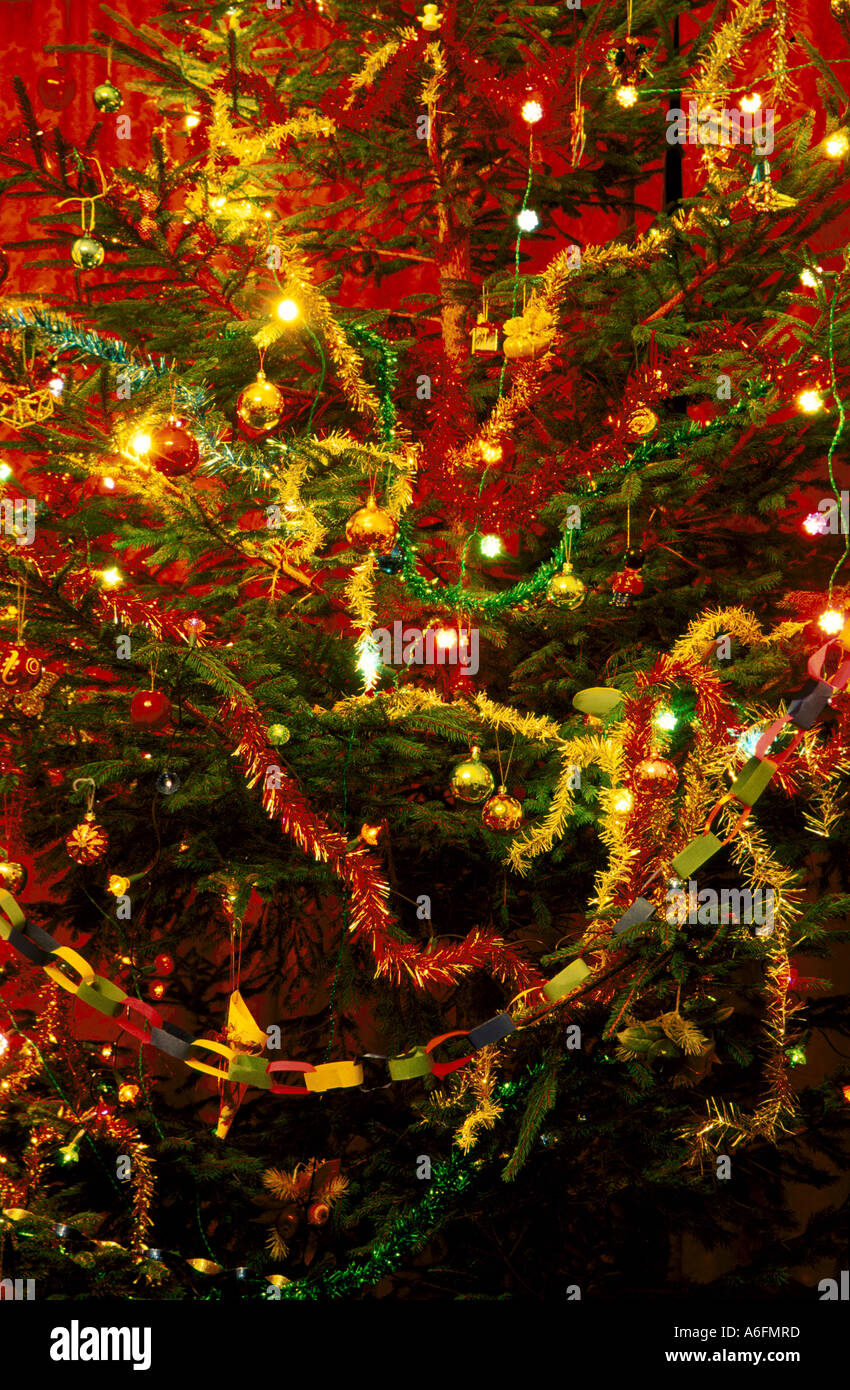 Albero di natale con decorazioni palline per l'albero campane luci catene di carta e tinsel Foto Stock