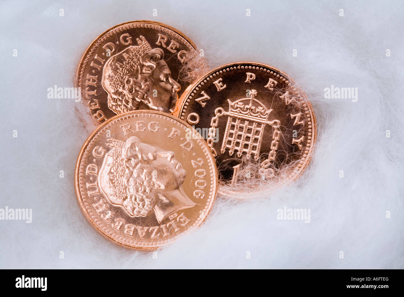 Tre UK penny di rame monete in close up avvolto in lana di cotone per la protezione Foto Stock