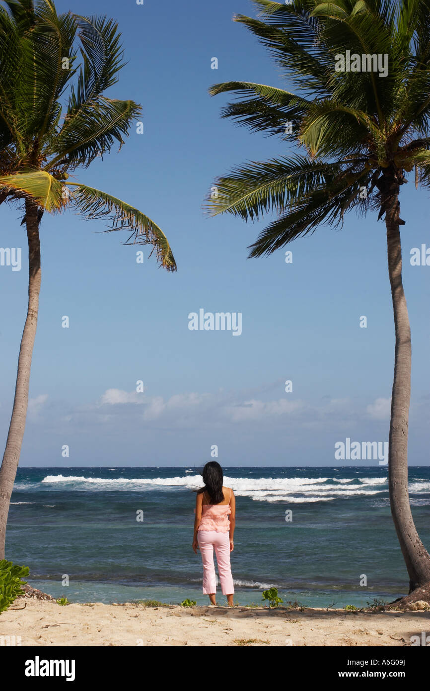 La donna in piedi tra due palme che dava sull'oceano Foto Stock