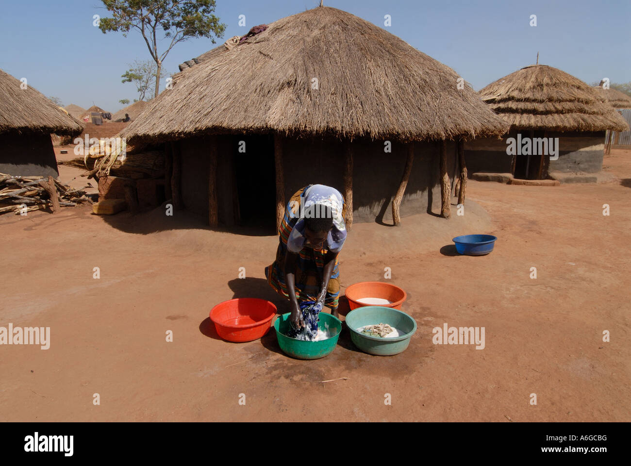 Per il campo per sfollati dal conflitto istigata da parte del Lord s Resistance Army donna lavaggio piatti nella parte anteriore del suo rifugio Foto Stock